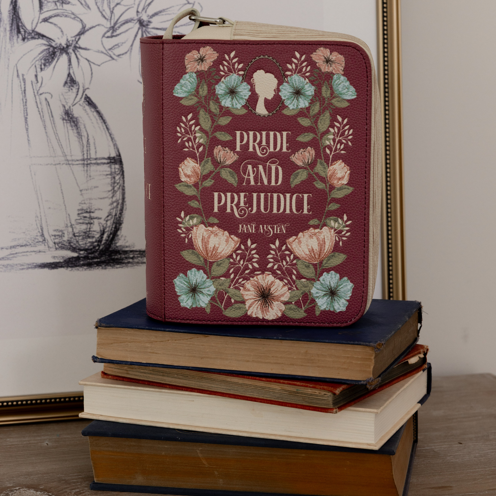 Book cover of 'Pride and Prejudice' by Jane Austen on a stack of books with floral design.