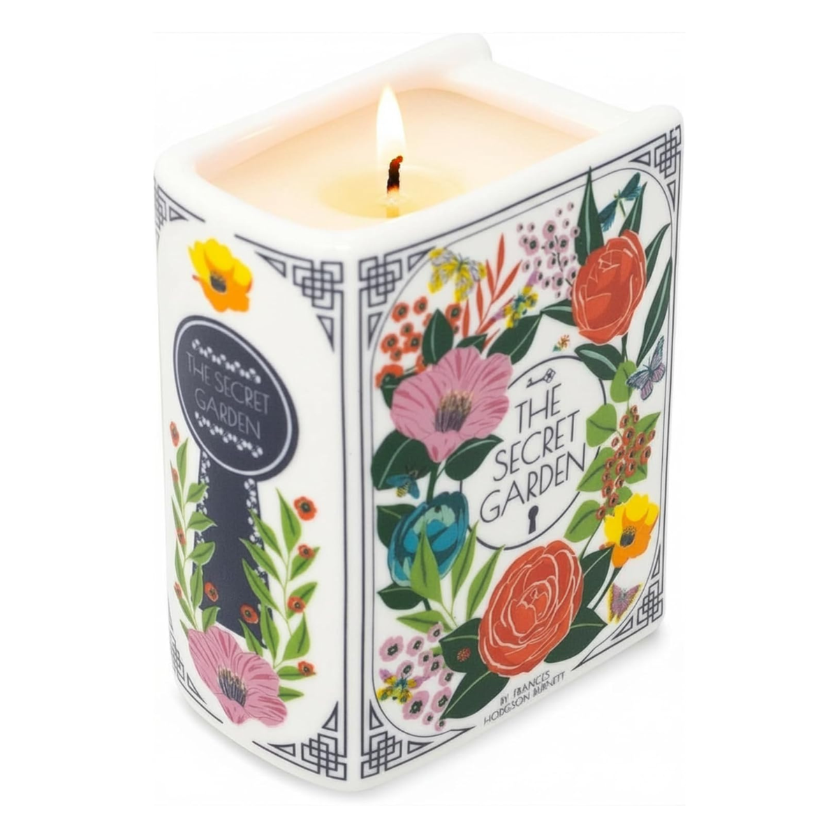 A square white scented candle labeled 'The Secret Garden' with a lit wick, decorated with colorful botanical illustrations of flowers and leaves on a white background.