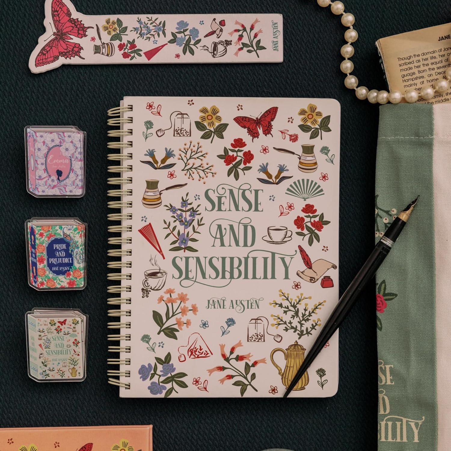 Notebook with 'Sense and Sensibility' design, surrounded by decorative items on a dark surface.