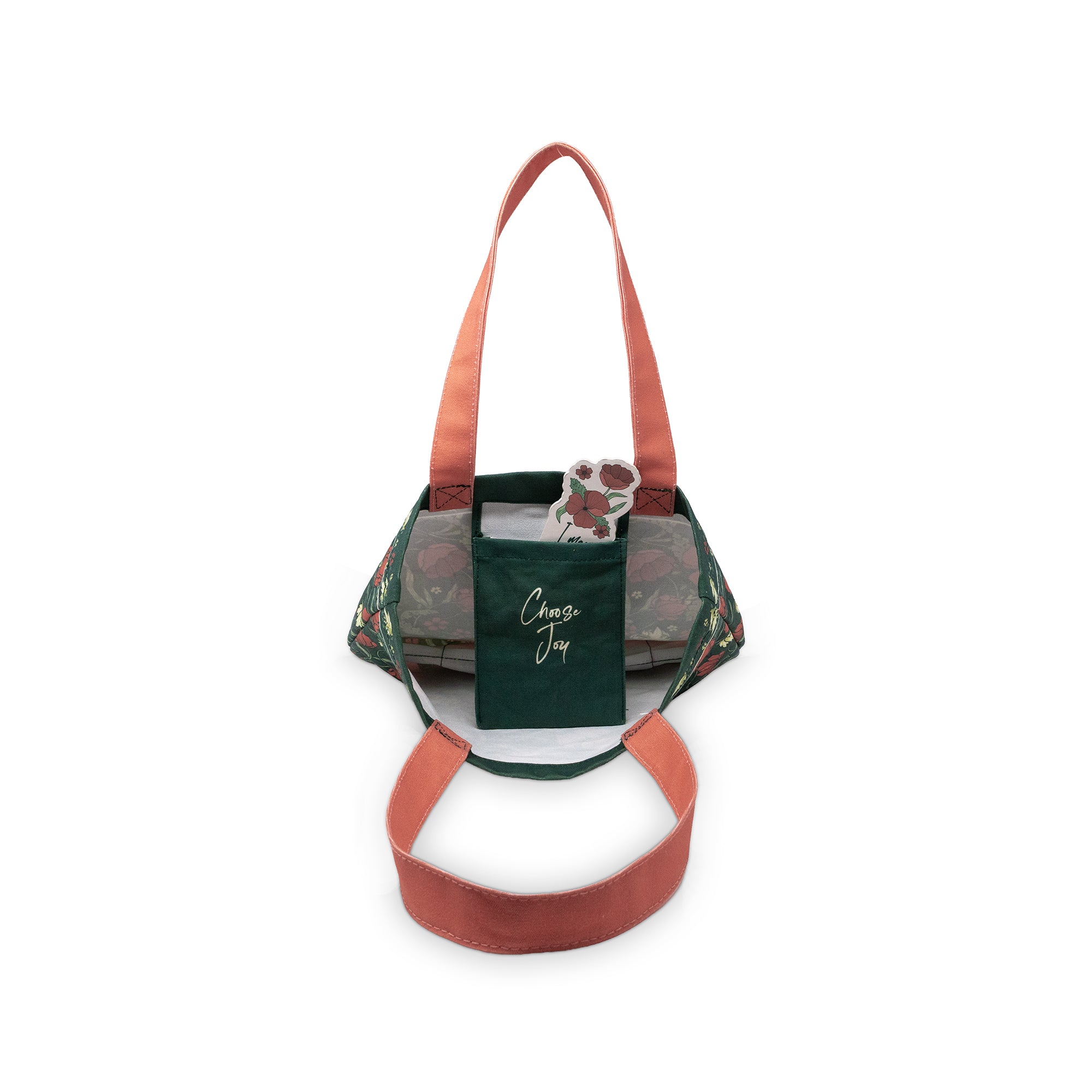 A bag with a dark green front pocket featuring the script logo 'Choose Joy' patterned sides, and terracotta-colored handles and strap, shown on a plain white background.