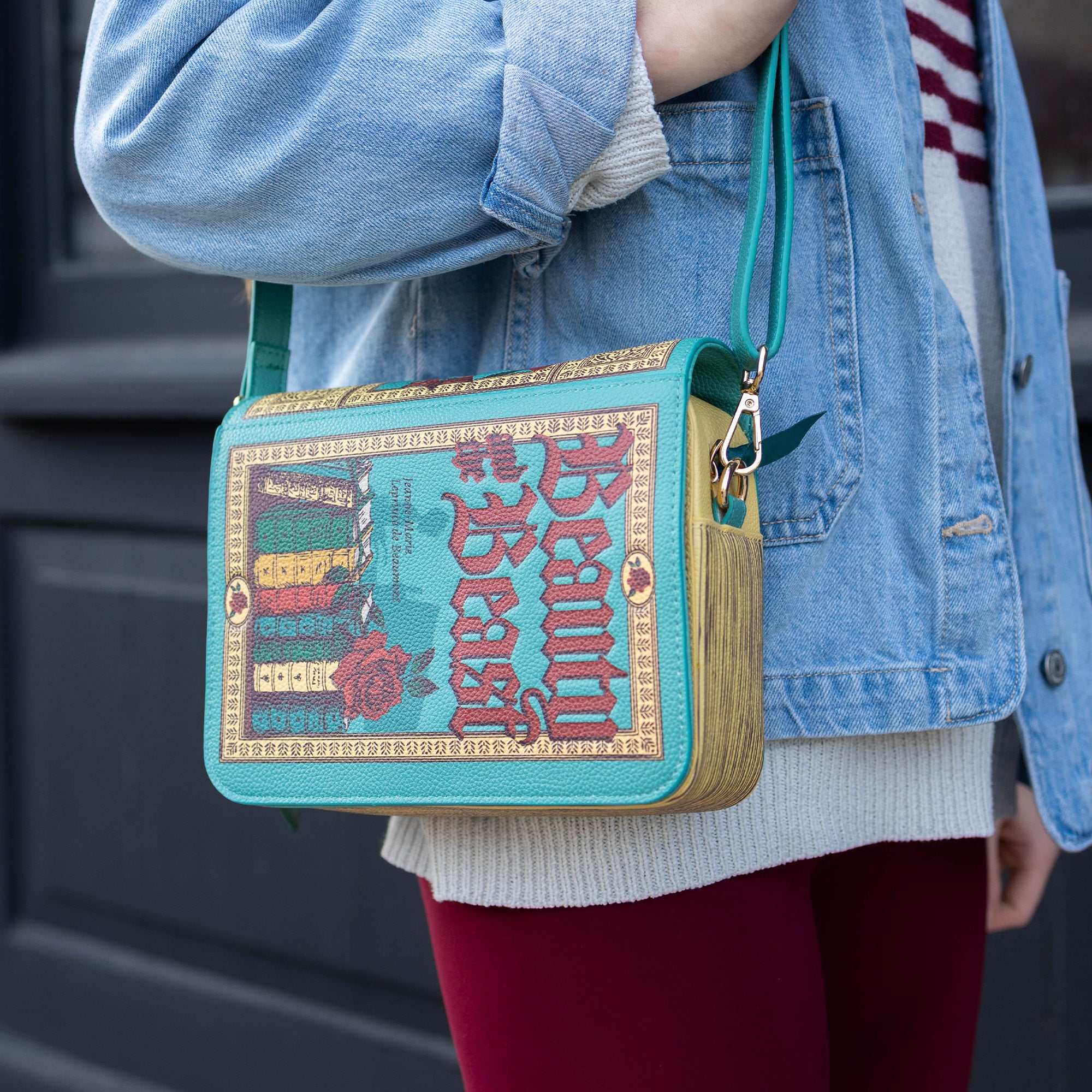 Person wearing a 'Beauty and the Beast' themed handbag with a blue and gold design.