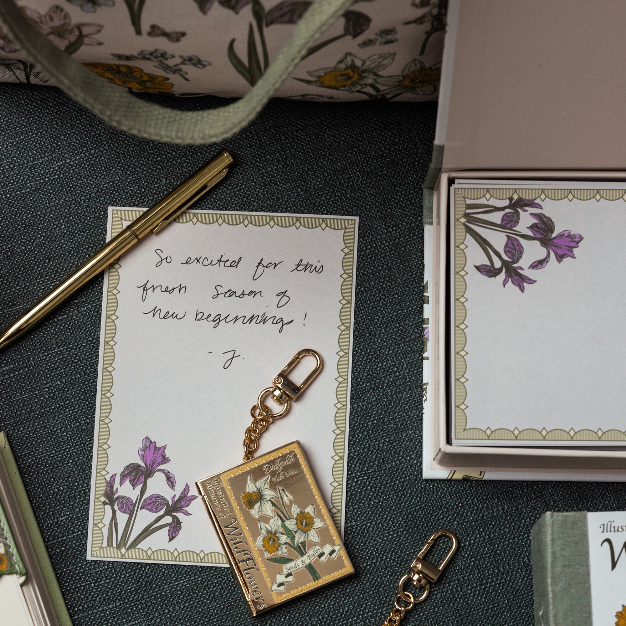 Keychain with floral design, card, and stationery items on a textured surface