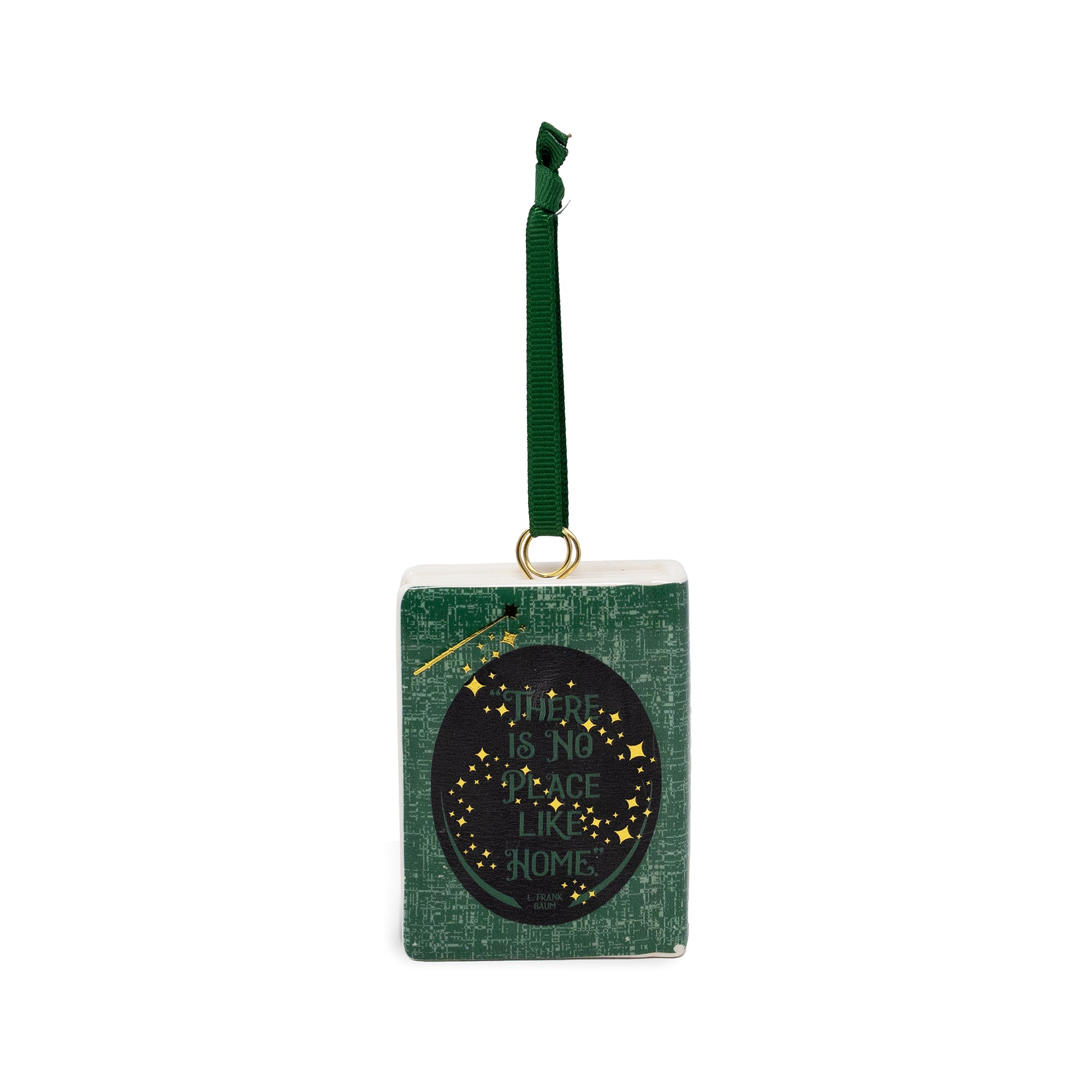 A rectangular green ornament with a hanging ribbon and a black oval label that reads 'There is no place like home' in gold lettering with small gold stars.