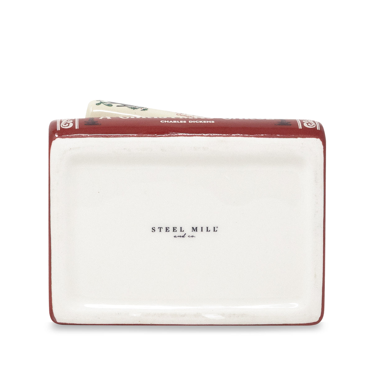 A rectangular ceramic money box designed to look like a vintage book, featuring a white cover with 'STEEL MILL and Co.' printed in black, and a dark red spine with gold decorative details.