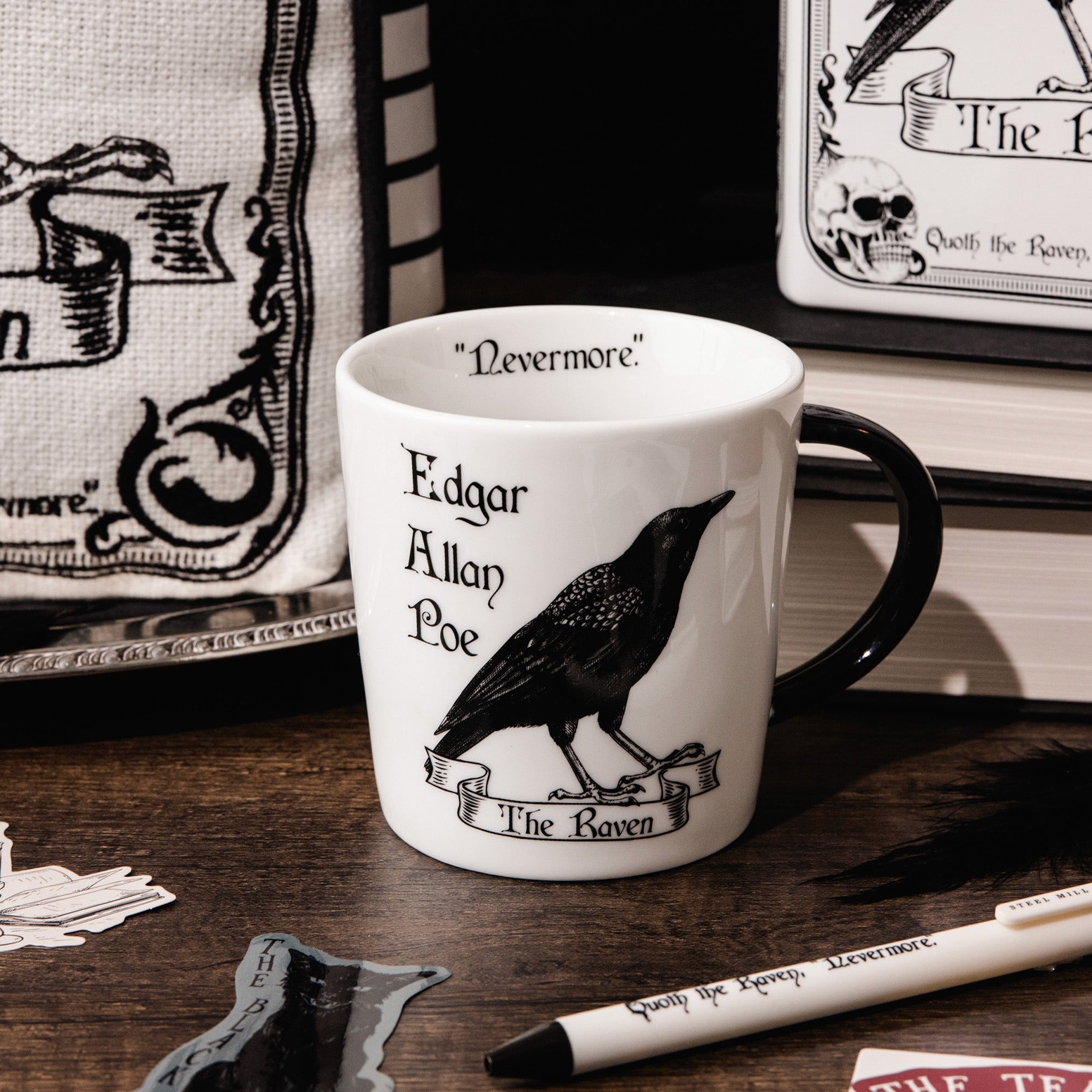 A white ceramic mug with a black handle, featuring a black illustration of a raven and the text 'Edgar Allan Poe' and 'The Raven' printed on the side.
