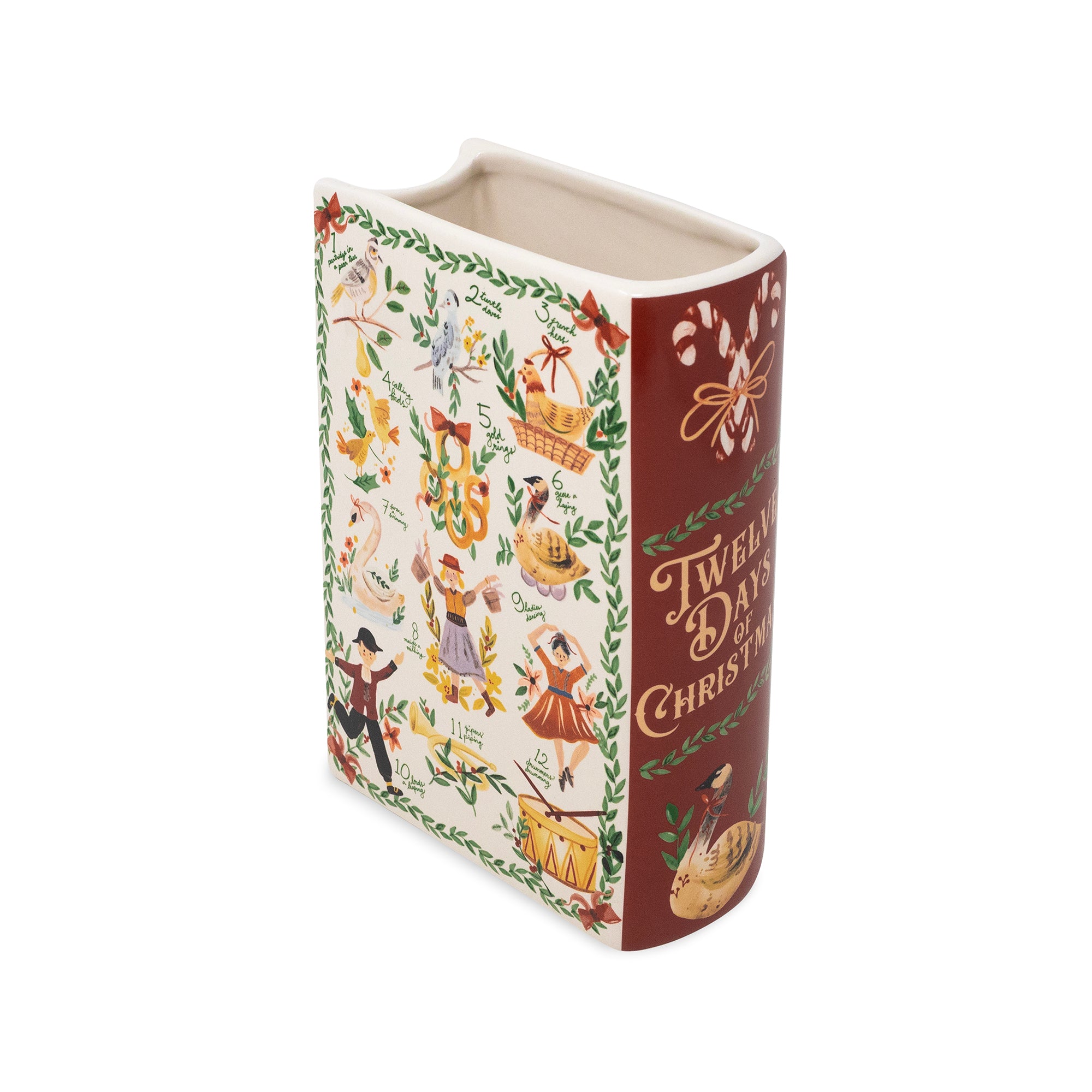 A ceramic book-shaped vase featuring a vintage Christmas design with illustrations and the text 'Twelve Days of Christmas' on a white background.