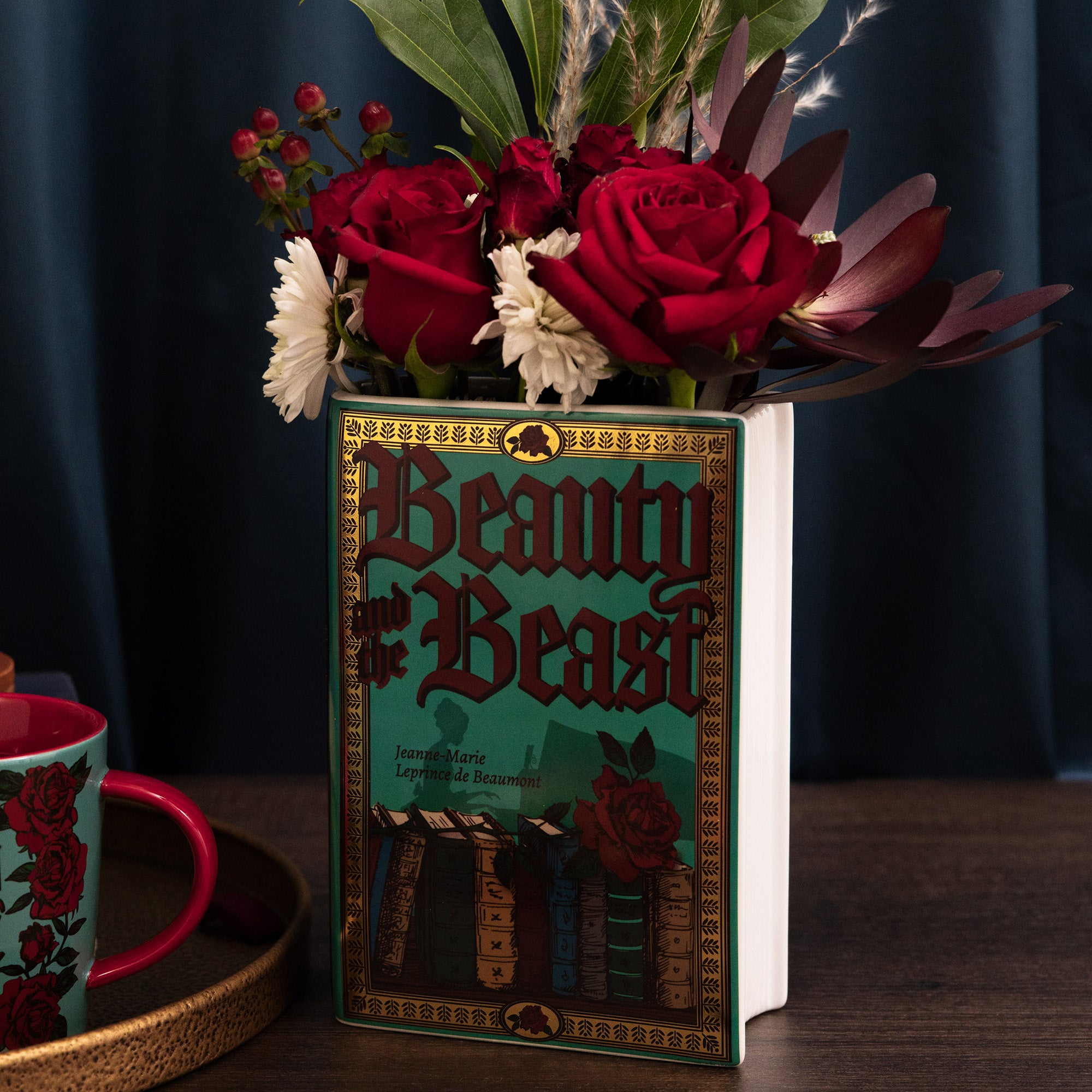 teal book shaped vase with beauty and the beast cover with flowers inside