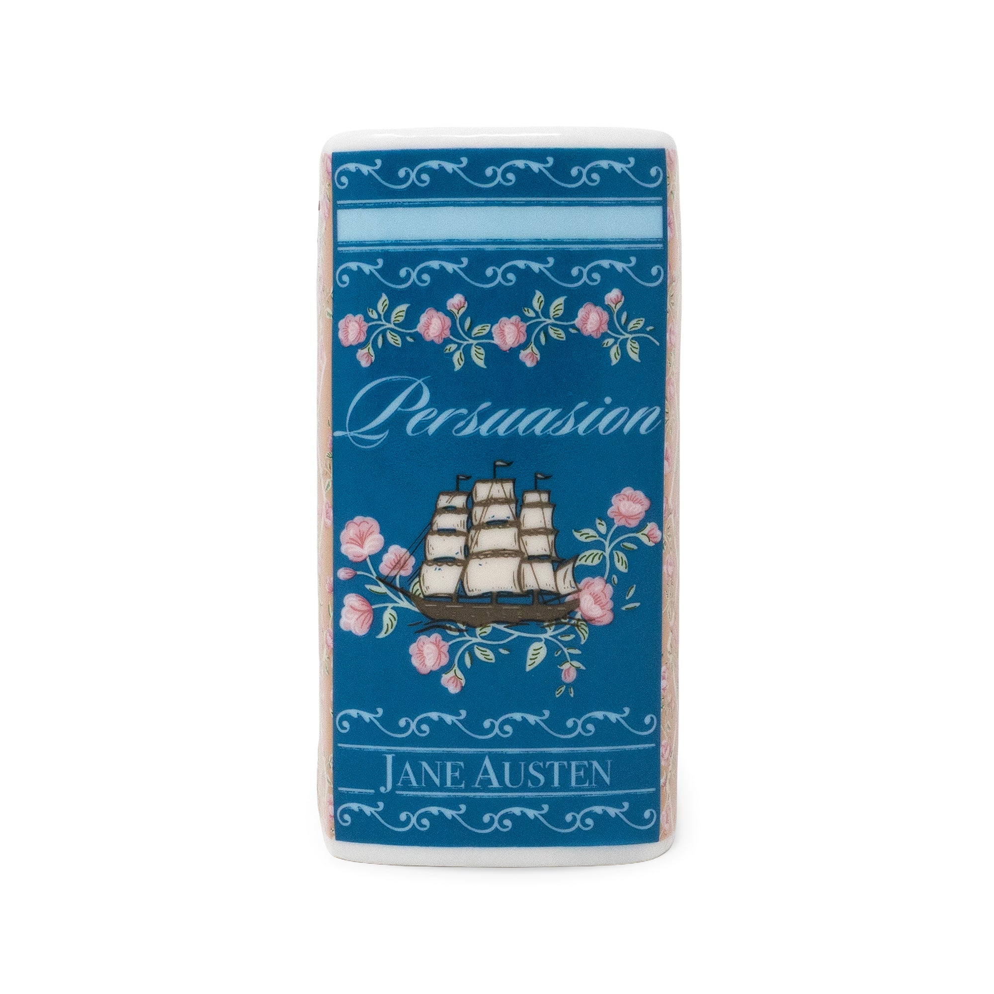A rectangular ceramic candle with rounded corners featuring a blue cover printed with pink roses, a sailing ship, the word 'Persuasion,' and 'Jane Austen' in white lettering.