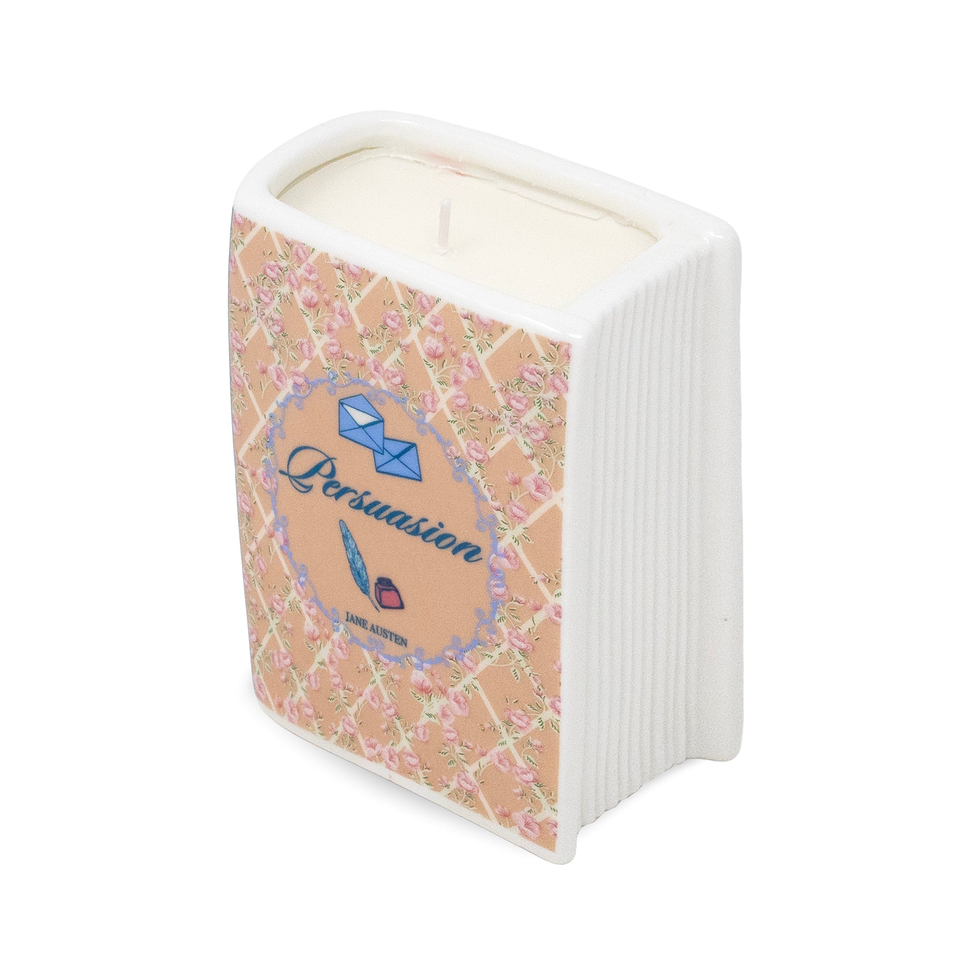 A novelty candle shaped like a book, featuring a beige cover with a pink floral lattice pattern and a blue circular label that reads 'Persuasion' with a feather and small envelope illustration. The book has white side panels and a white wax fill, shown on a plain white background.