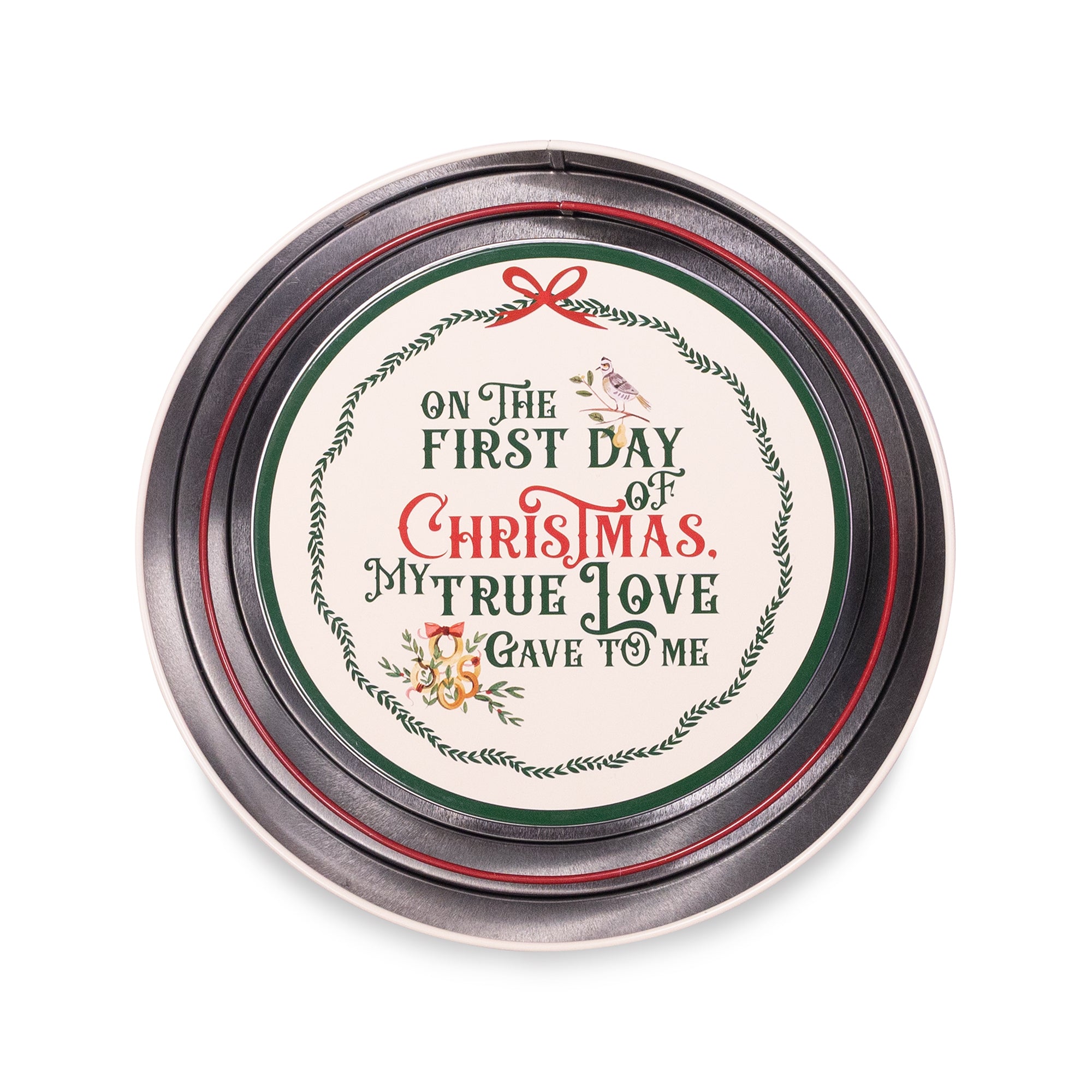 A round tin of scented candles with a silver metal lid featuring a festive Christmas design. The lid has a cream-colored center with the text 'ON THE FIRST DAY OF CHRISTMAS, MY TRUE LOVE I GAVE TO ME' in green and red lettering, surrounded by a wreath border, a small bird, and a red bow.