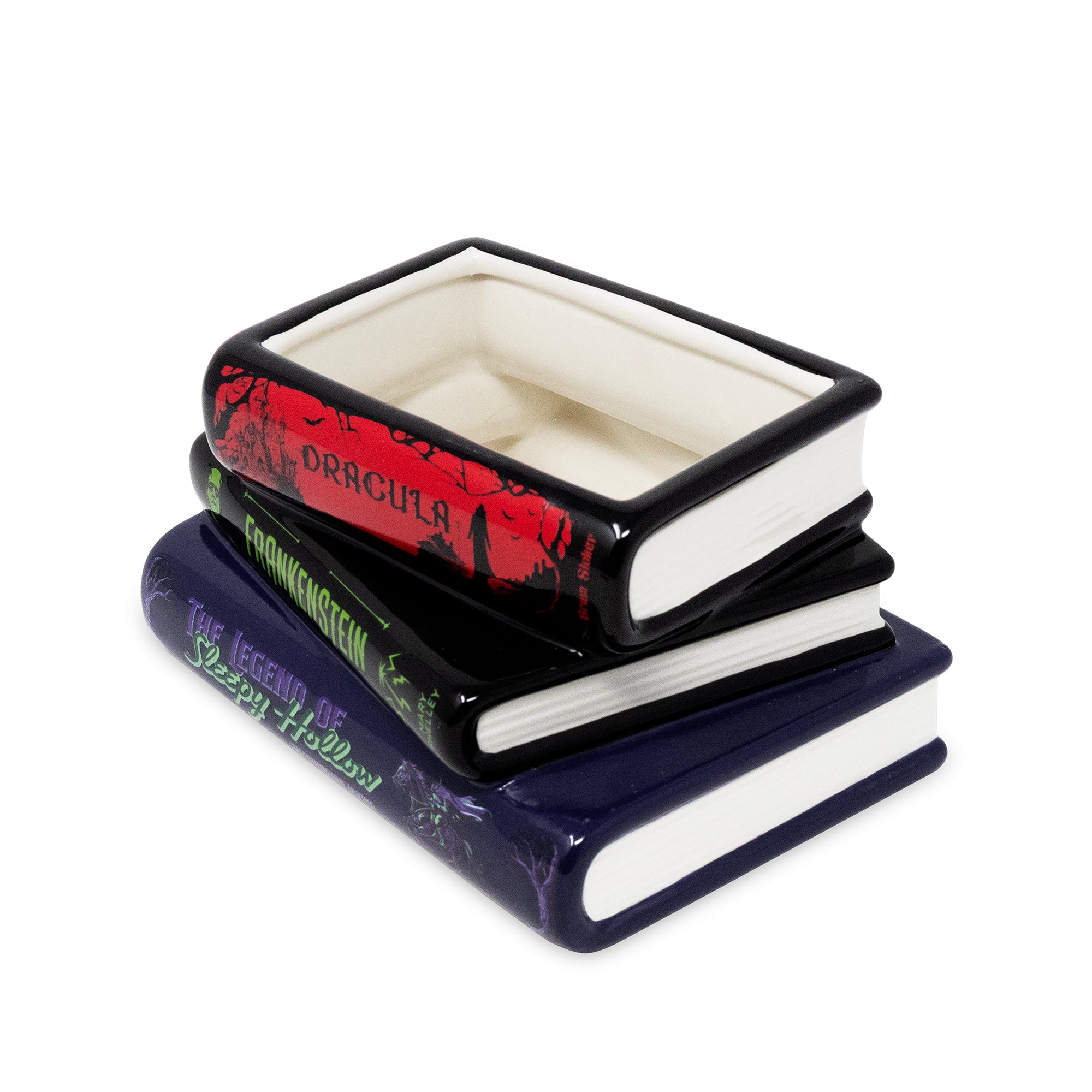A ceramic Halloween-themed book stack vase, featuring 'Dracula' in red and black, 'Frankenstein' in black and green, and 'The Legend of Sleepy Hollow' in dark blue and white.