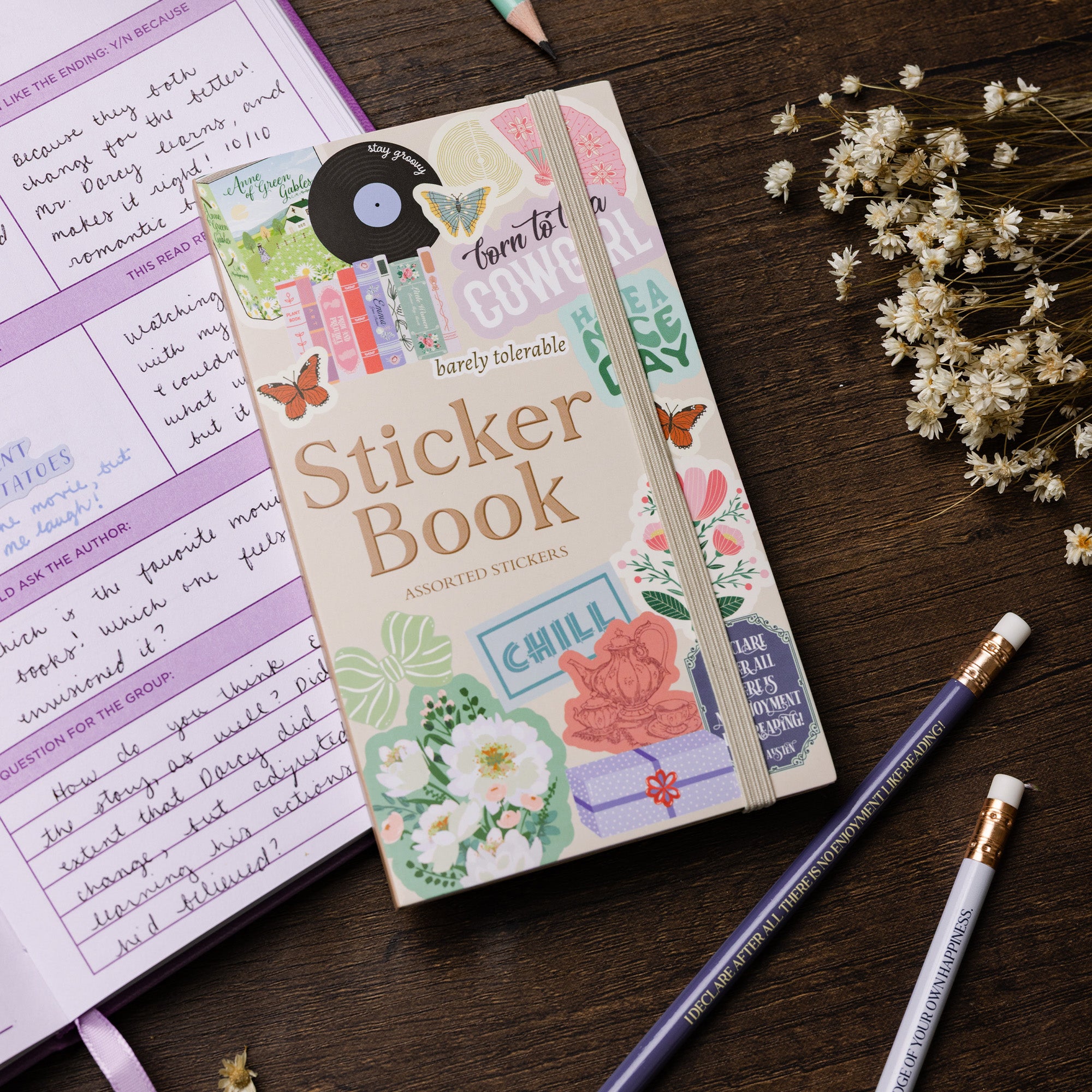 Sticker book on a wooden surface with a notebook and pencils