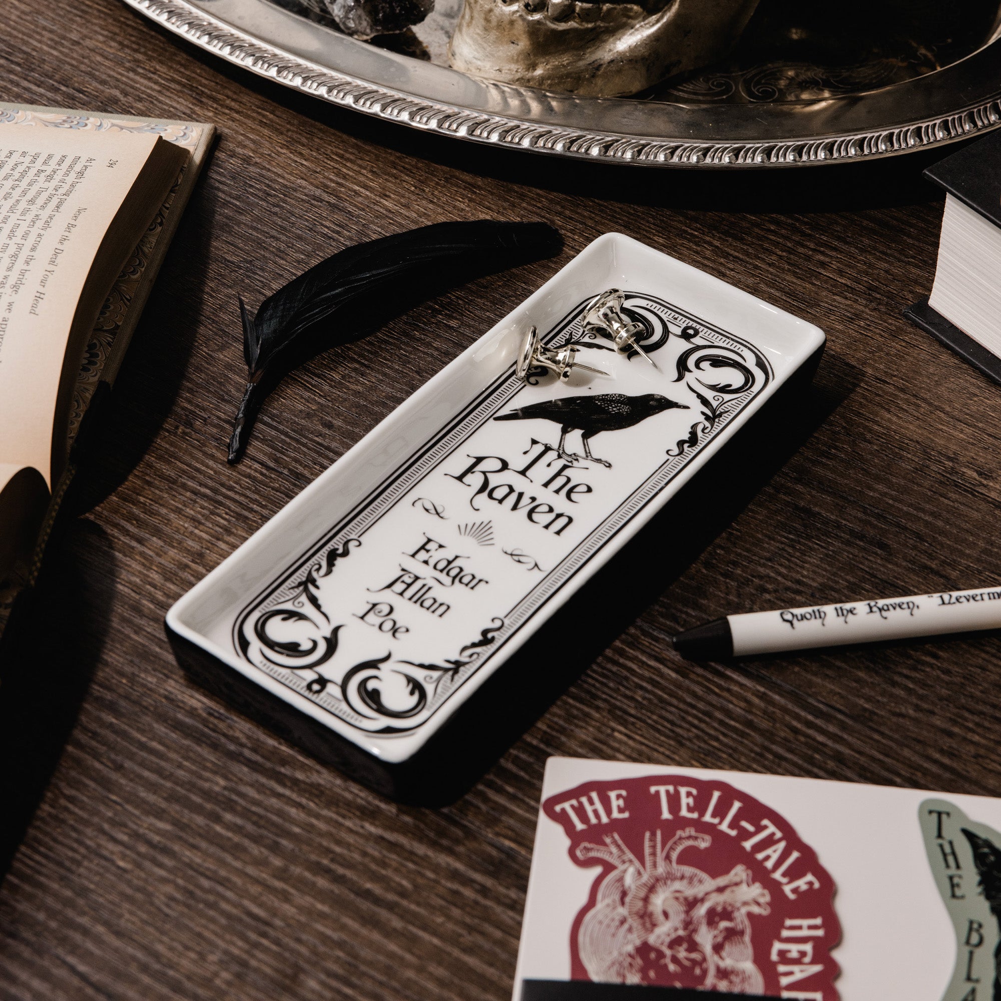 side view of white rectangular tray featuring a black ornate border, a raven illustration, and the text 'The Raven' and 'Edgar Allan Poe' printed in black.