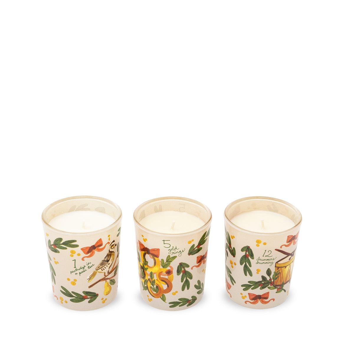 Three small glass jar candles with cream-colored wax and holiday illustrations, arranged in a row on a plain white background.