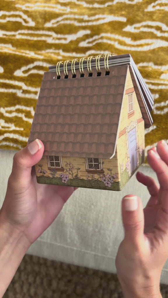 model flipping through house-shaped spiral-bound quote deck with decorative cover