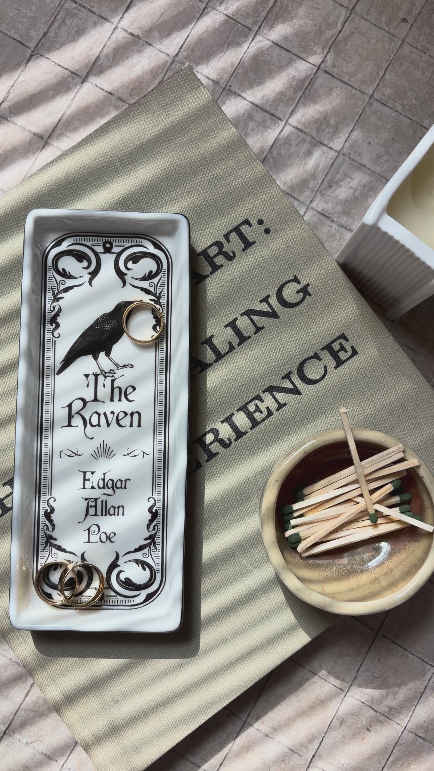 model showcasing white rectangular tray featuring a black ornate border, a raven illustration, and the text 'The Raven' and 'Edgar Allan Poe' printed in black.
