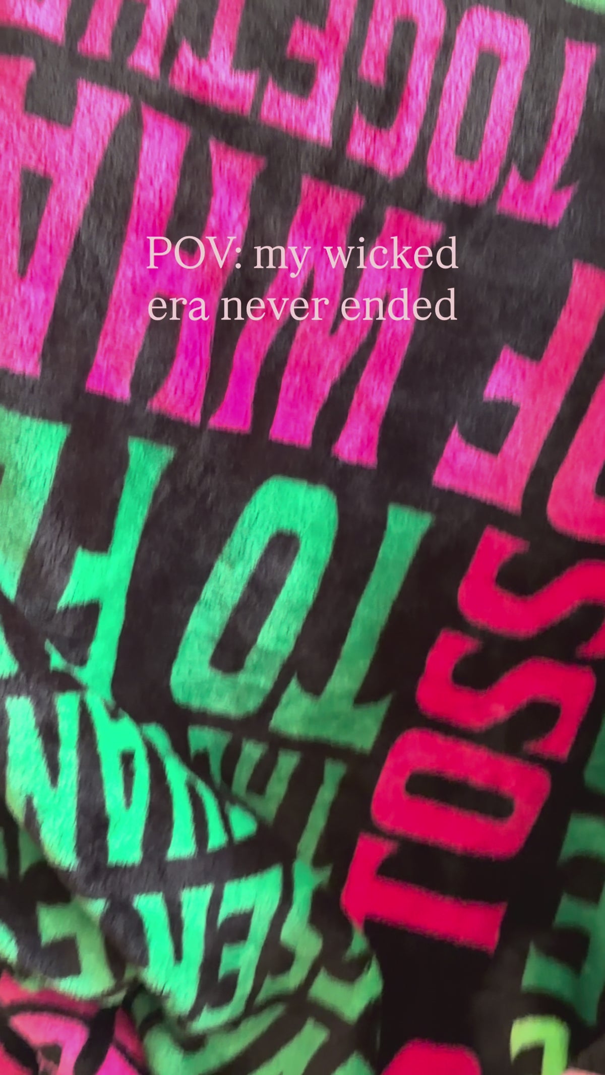 model cozying up with green and pink wicked blanket